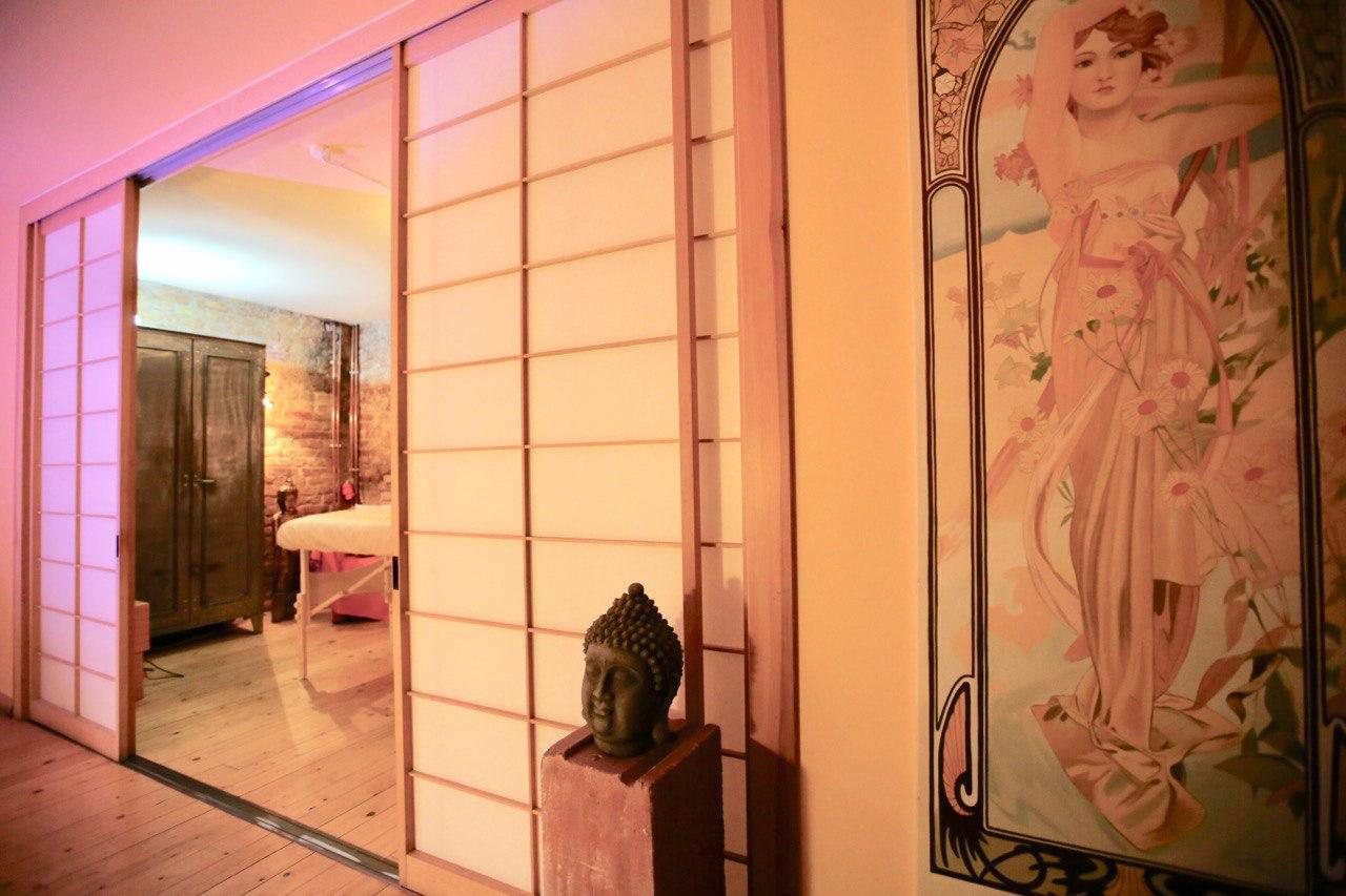 Sliding paper screens open onto a treatment room, beside an Art Nouveau mural