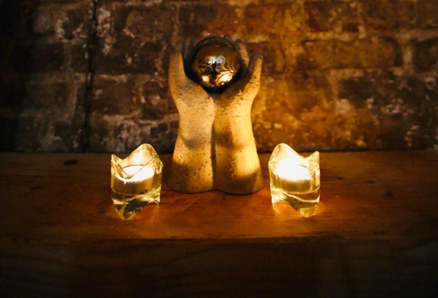 A stone sculpture of cupped hands between two lit tealights