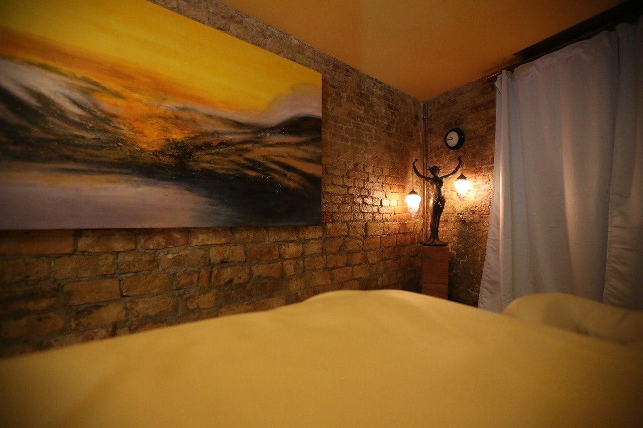 A treatment room with bare brick walls, a large painting and two glowing lamps